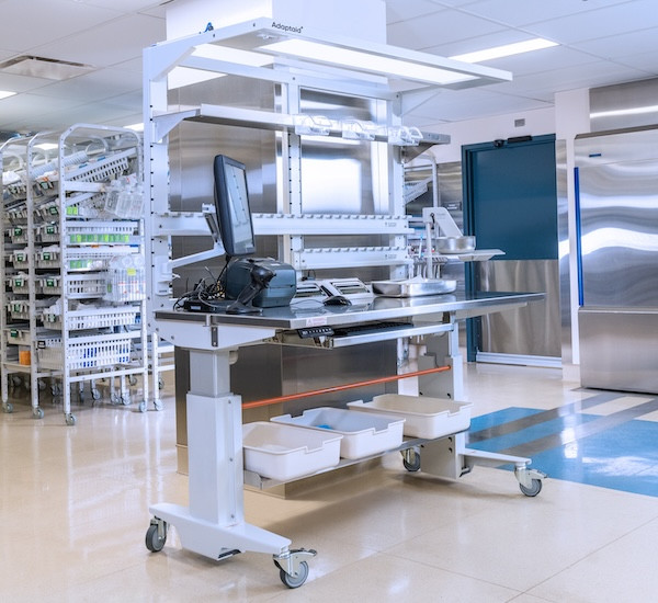 Meilleure station de travail en acier inoxydable résistant à la corrosion, réglable en hauteur, avec module supérieur et accessoires d'emballage des instruments chirurgicaux photographiés dans un service de retraitement des dispositifs médicaux.